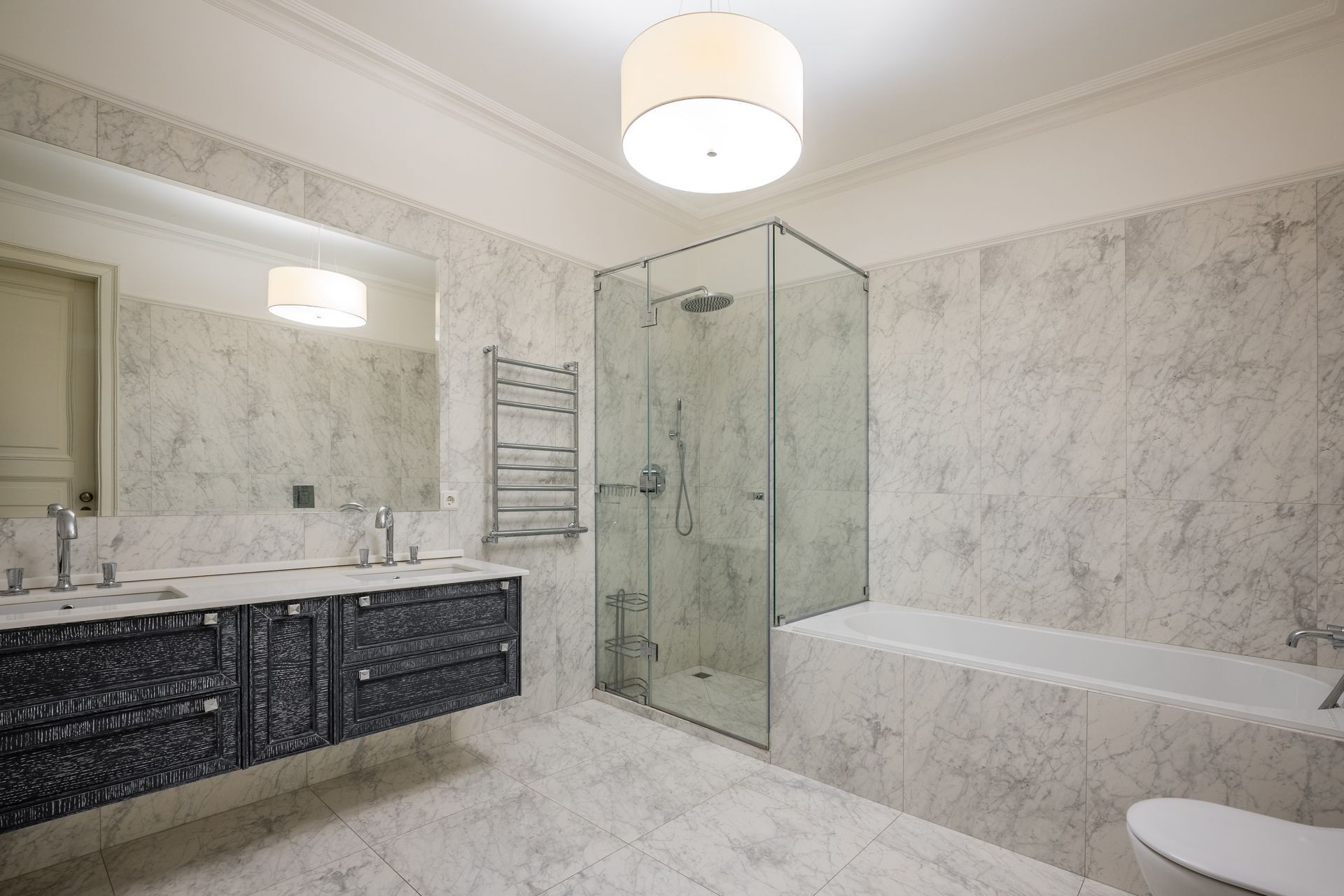 Modern bathroom with marble walls, shower, bathtub, and vanity with double sinks.