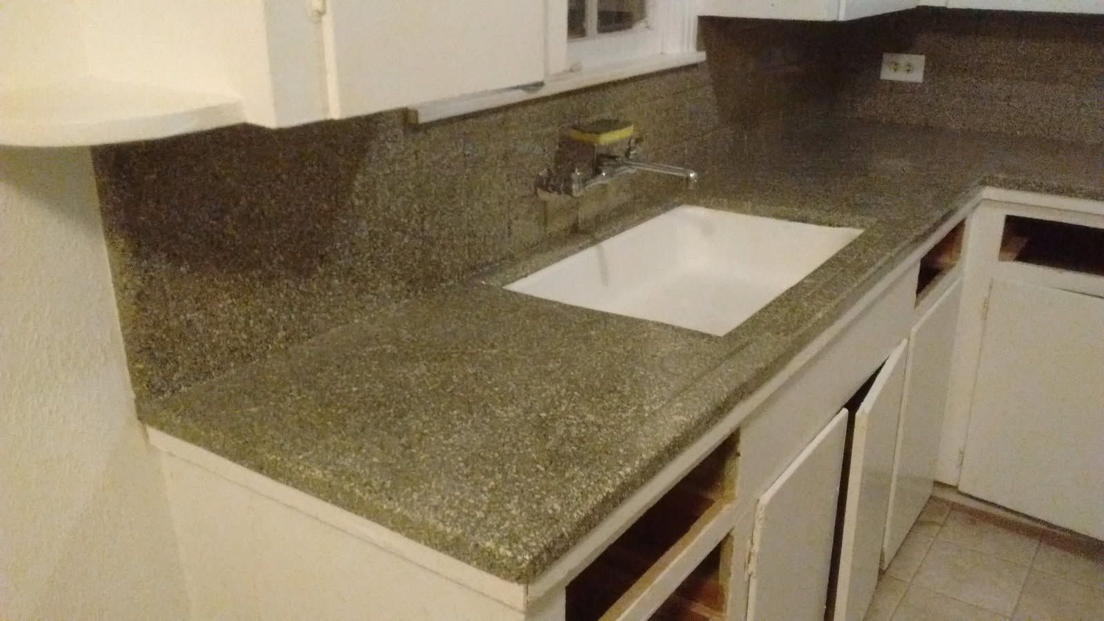 White kitchen cabinets with gray speckled countertop and sink.