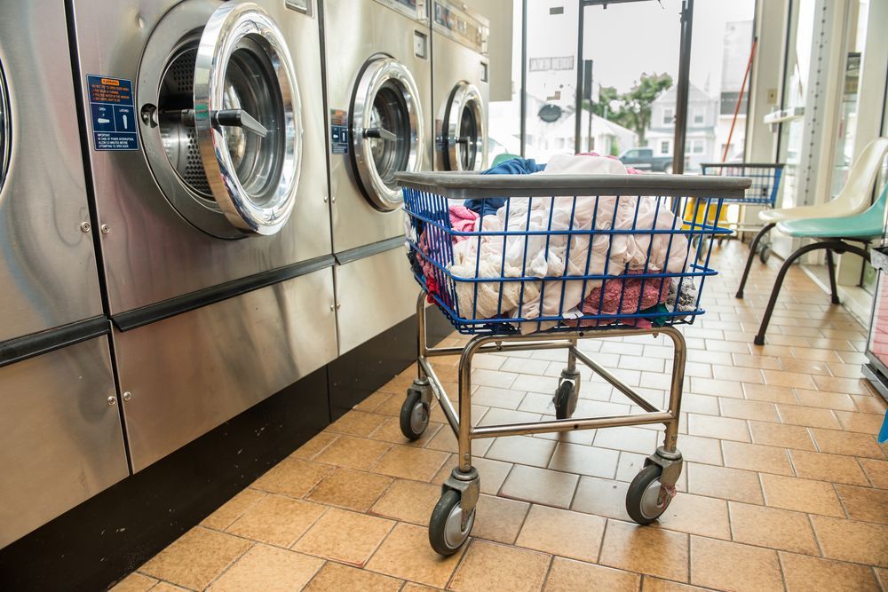 Shopping Trolley Full Of Clothes In Front Of Wall Of Washing Machines — Dapto Swish & Swash Laundrette In Dapto, NSW