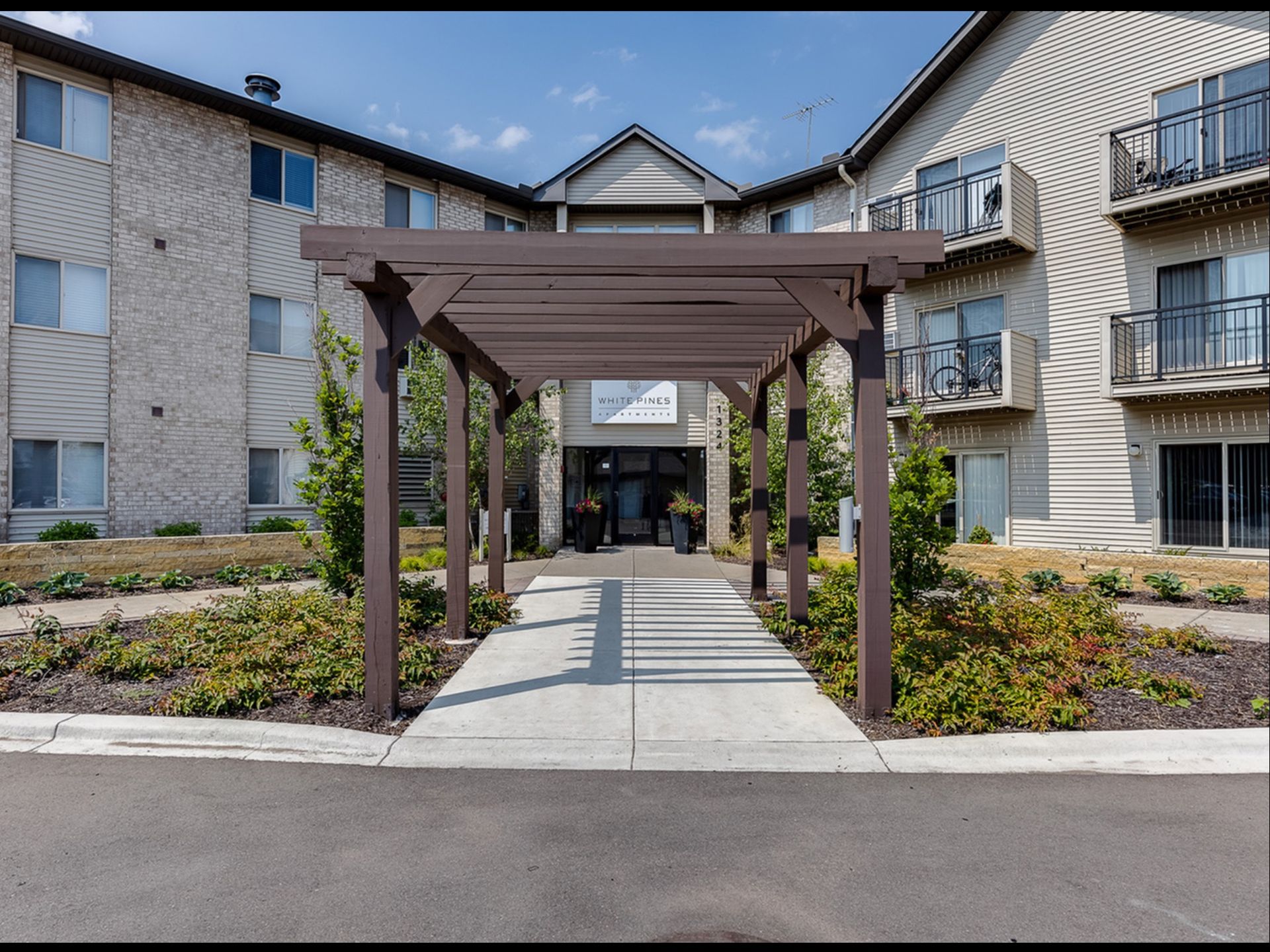 Exterior of a multi-family building with a wooden pergola walkway to the entrance.