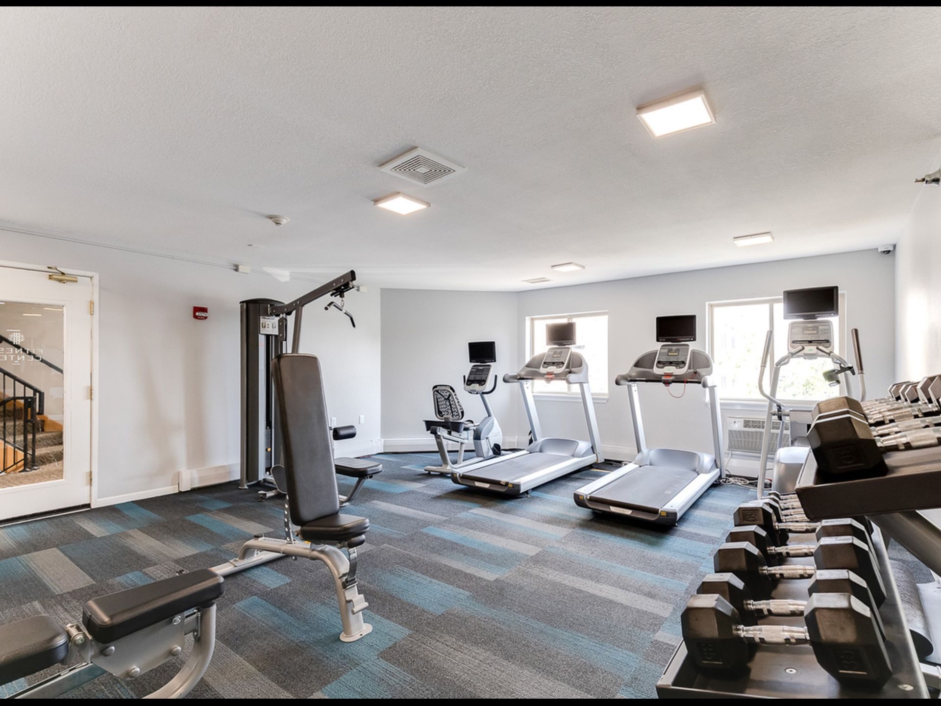 Fitness center with multiple cardio machines, weight benches, and free weights.