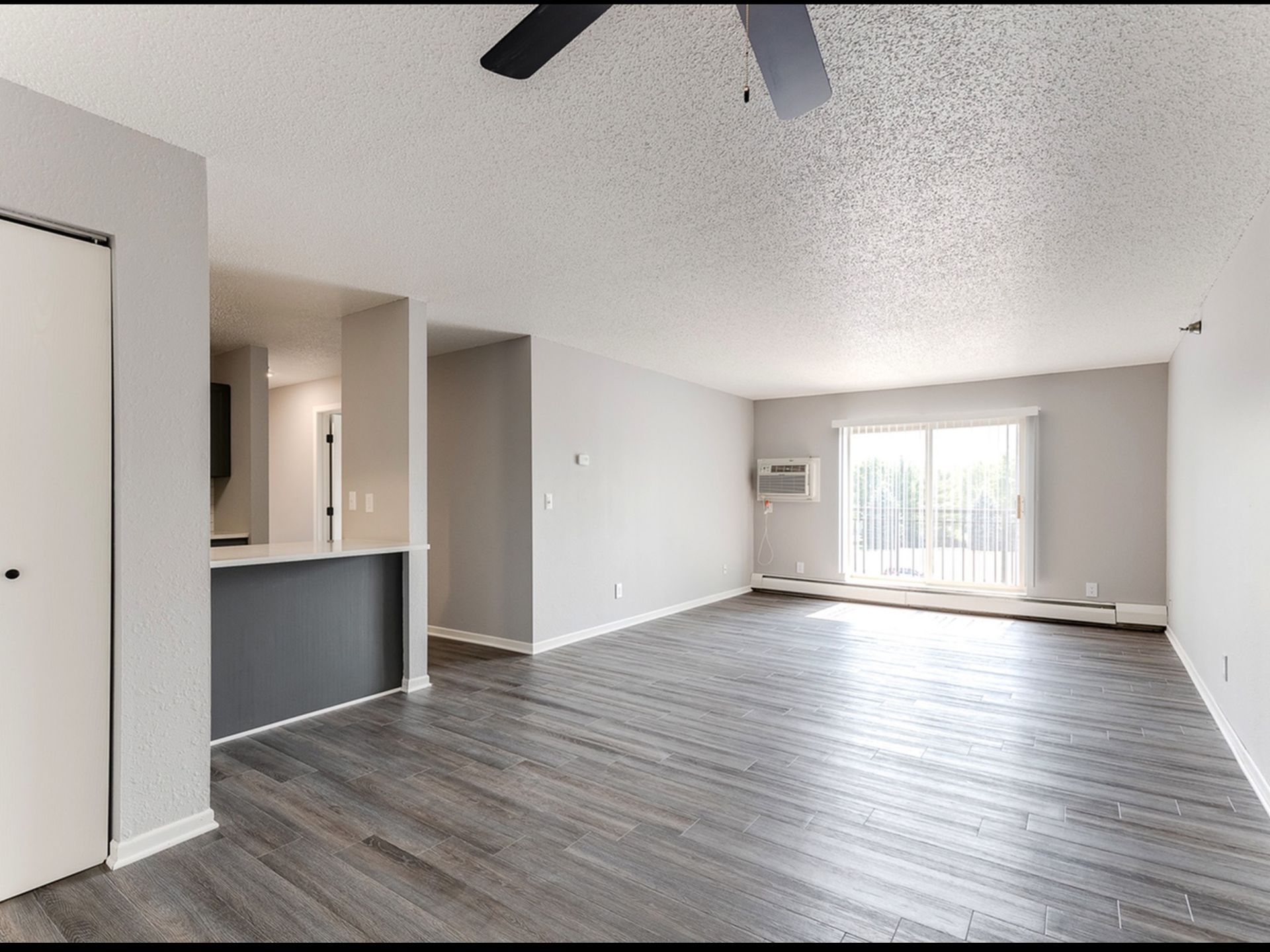 Open living room in a modern apartment with a kitchen bar and sliding balcony door.