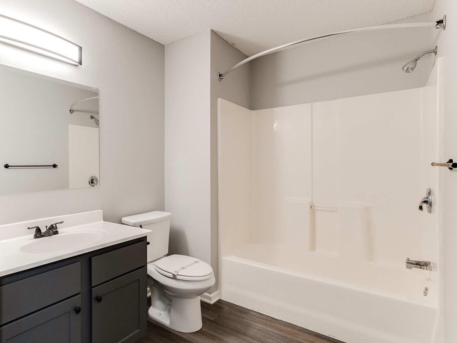 Bathroom in an apartment with a vanity, toilet, and shower-tub combo.