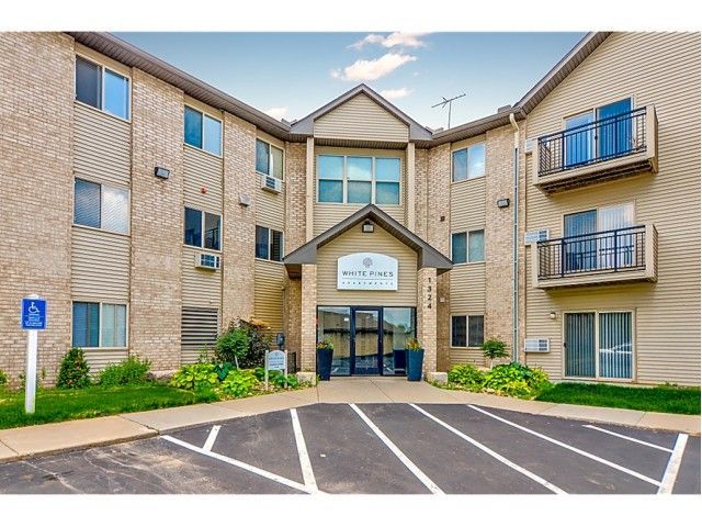 Exterior view of White Pines apartments entrance with landscaping and parking.