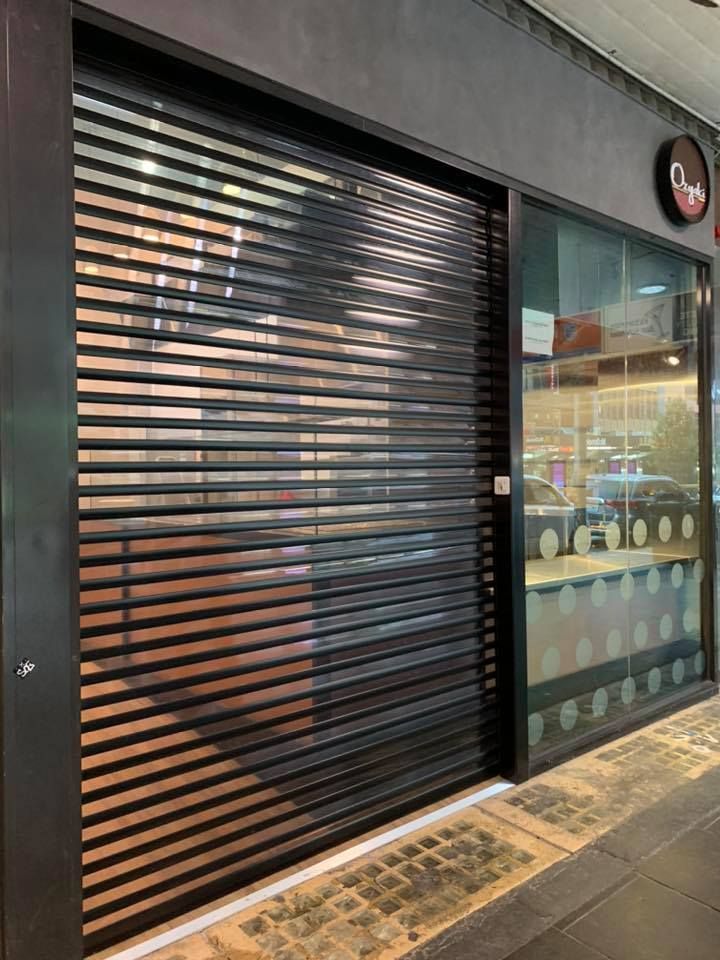 Shop Front With Perforated Roller Shutters — Window Shutters in Wollongong, NSW