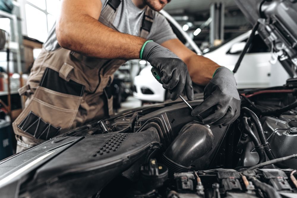 A man is working on the engine of a car in a garage.