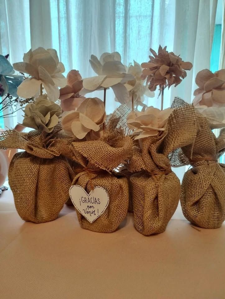 Recuerdos envueltos en arpillera con flores de papel frente a una ventana