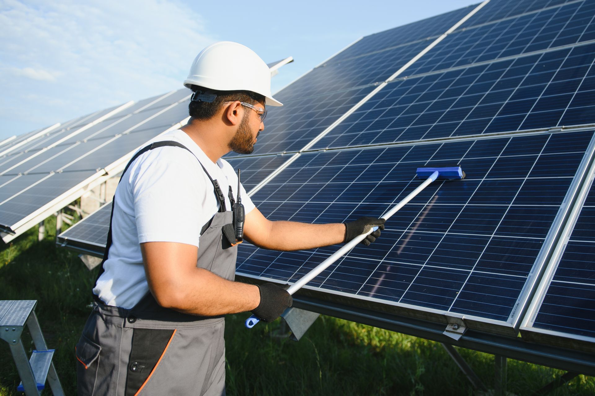 A man is commercial cleaning services solar panels with a brush.