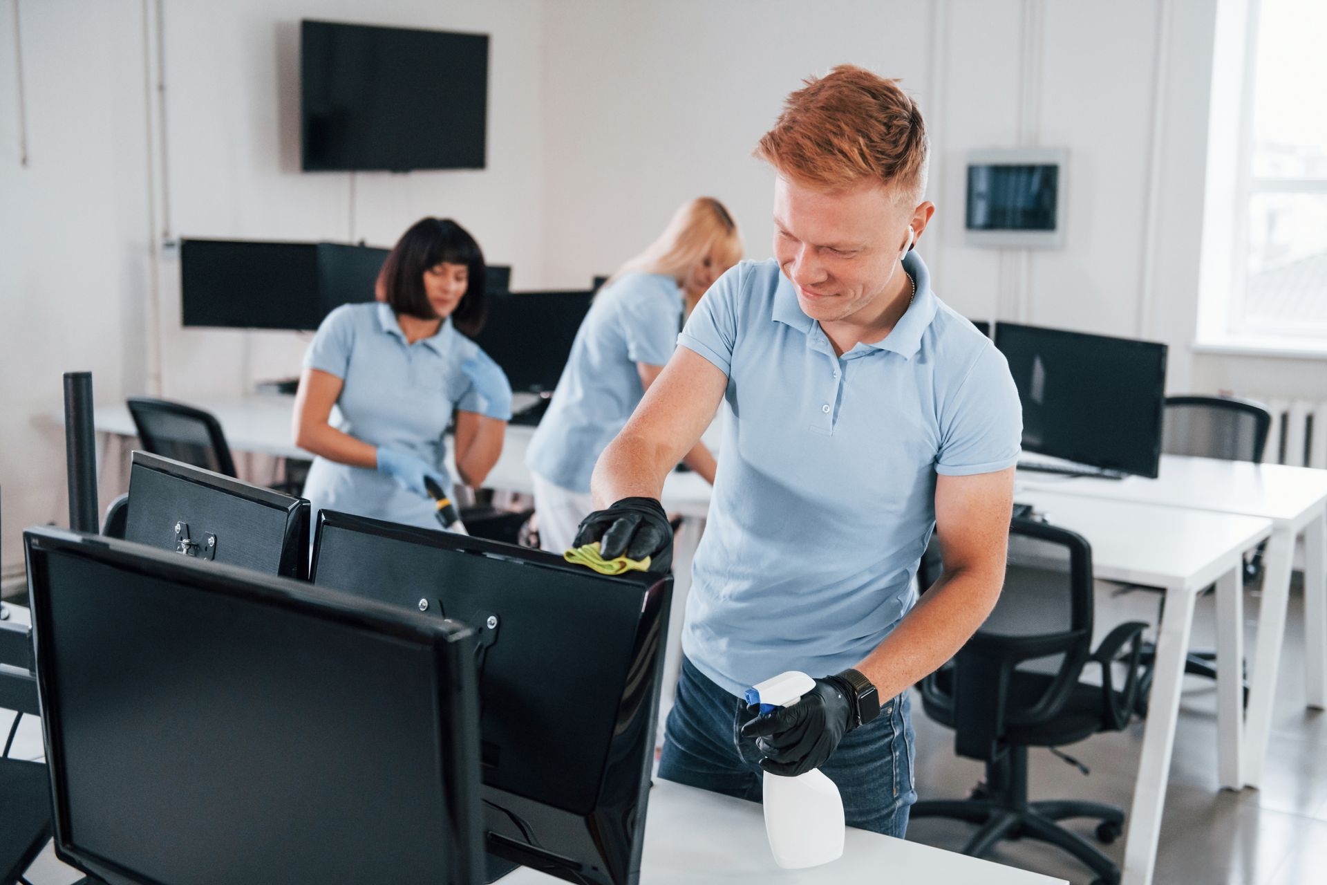 commercial cleaning services near me A man is cleaning a computer monitor in an office.