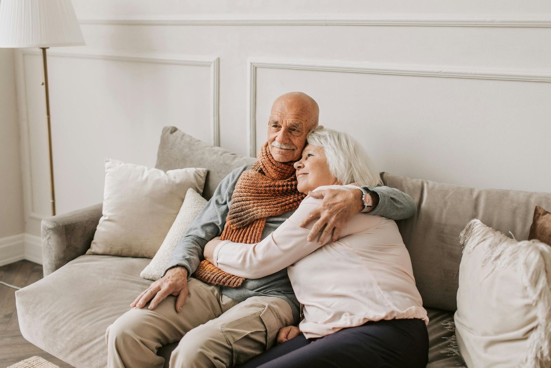 company of cleaning An elderly couple is sitting on a couch hugging each other.