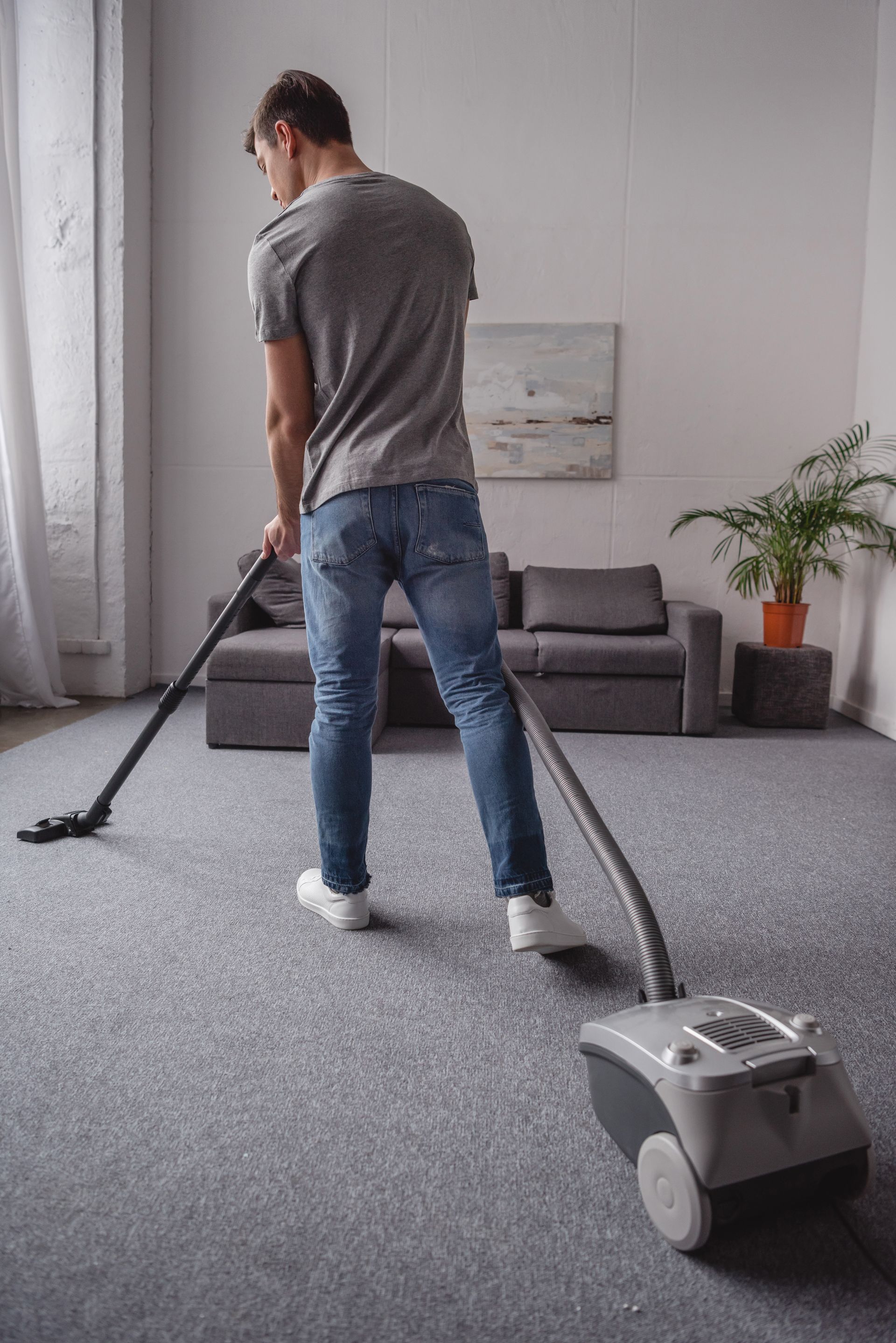 A man is vacuuming the carpet in a living room.