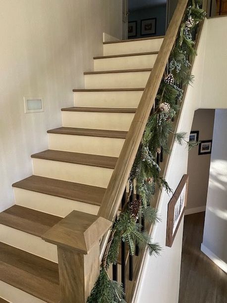 A wooden staircase with a christmas garland on the railing.
