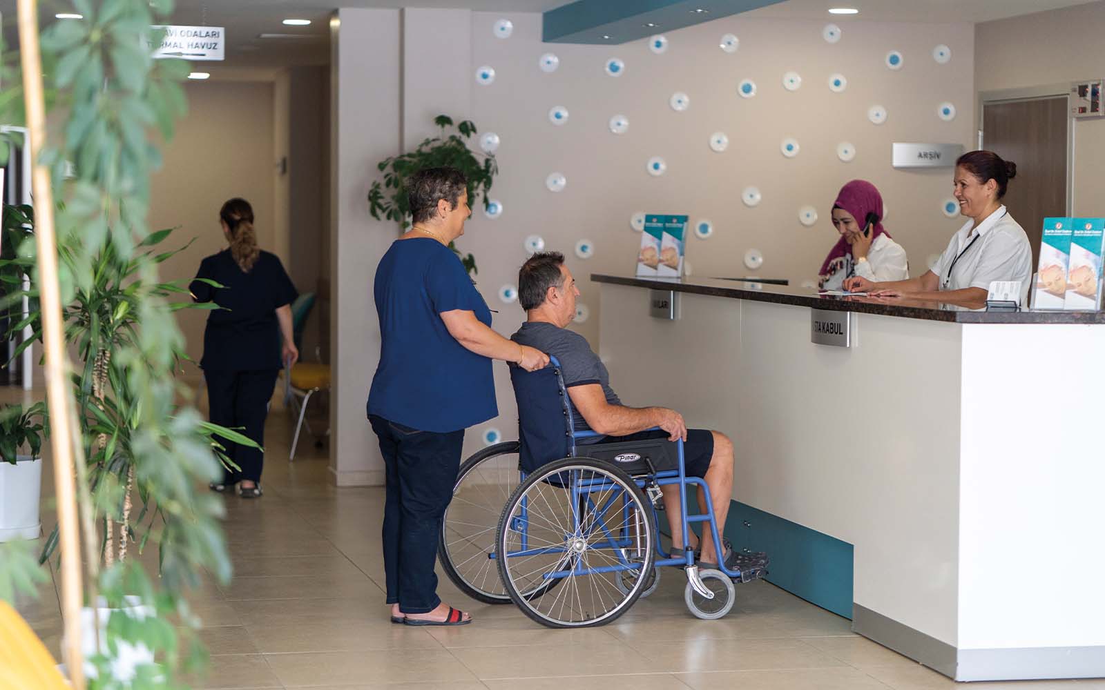 Tekerlekli sandalyedeki bir adam hastanedeki bir tezgahta oturuyor.