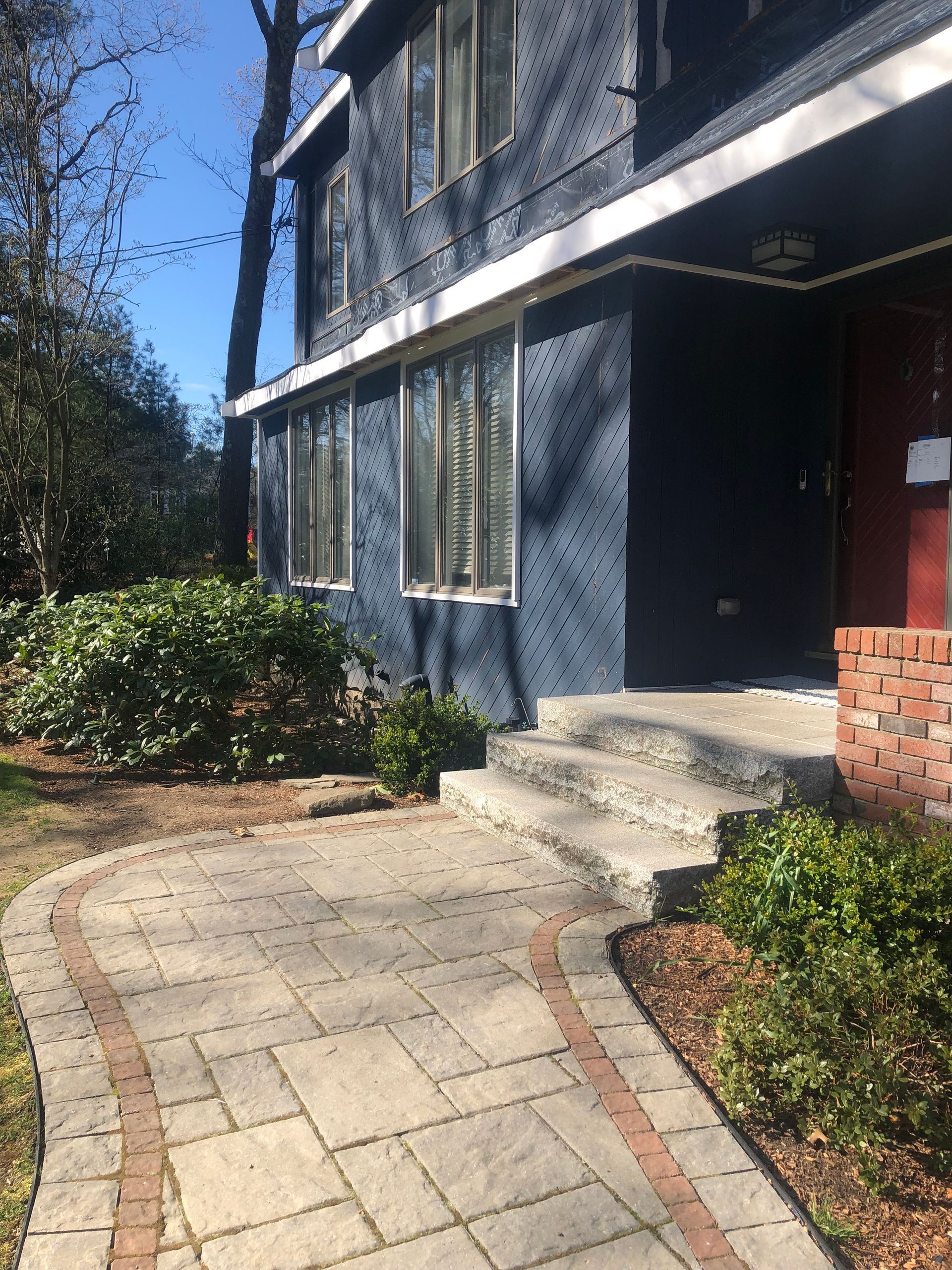 A blue house with a brick walkway and steps leading to the front door.