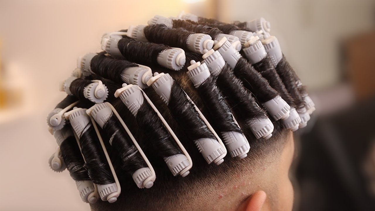 Männerkopf mit Dauerwellenhaar vor unscharfem Hintergrund.