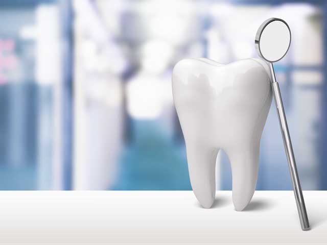 A tooth is sitting next to a dental mirror on a table.