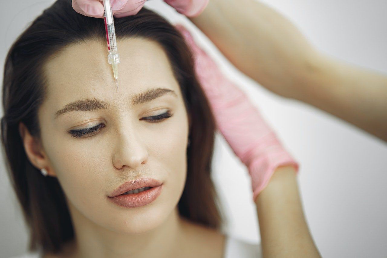 A woman is getting a botox injection on her forehead.