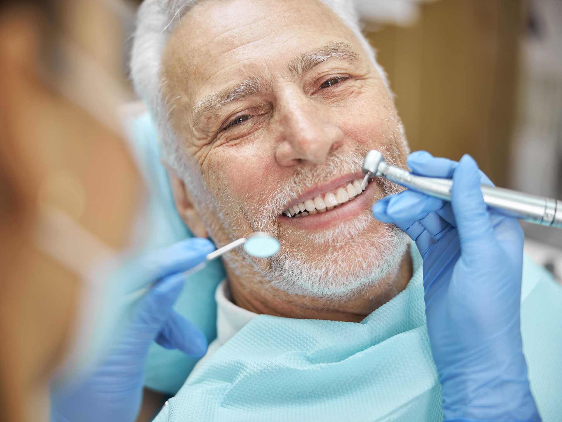 An elderly man is having his teeth examined by a dentist.