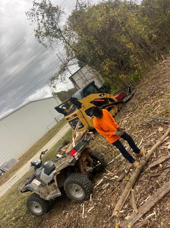 A man is standing next to a atv and a bulldozer.