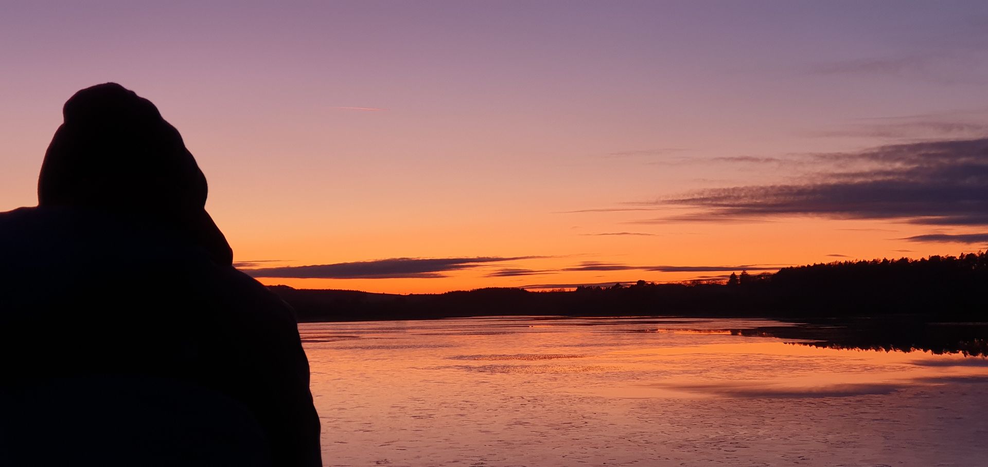 Image of male tourist on a Tartan Compass eco-tour watching the sunset over a loch at Bavelaw Estate, Pentland Regional Park near Edinburgh