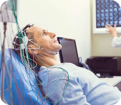 um homem está deitado em uma cama de hospital com fios presos à cabeça.