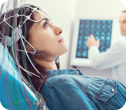 uma mulher está deitada em uma cama com fios em volta da cabeça e um médico está olhando para a tela de um computador.