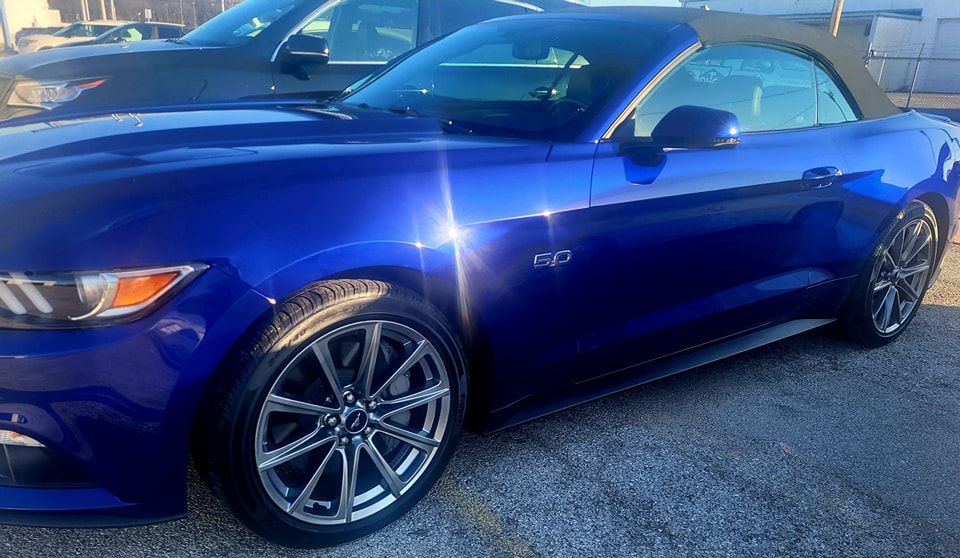 A blue mustang convertible is parked in a parking lot.