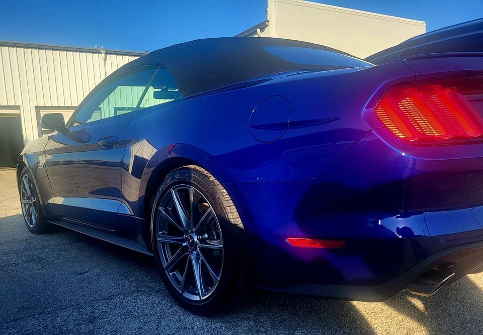 A blue ford mustang is parked in front of a building.