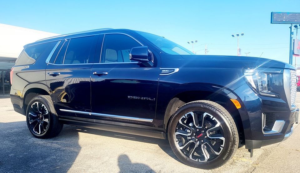 A black suv is parked on the side of the road in front of a building.