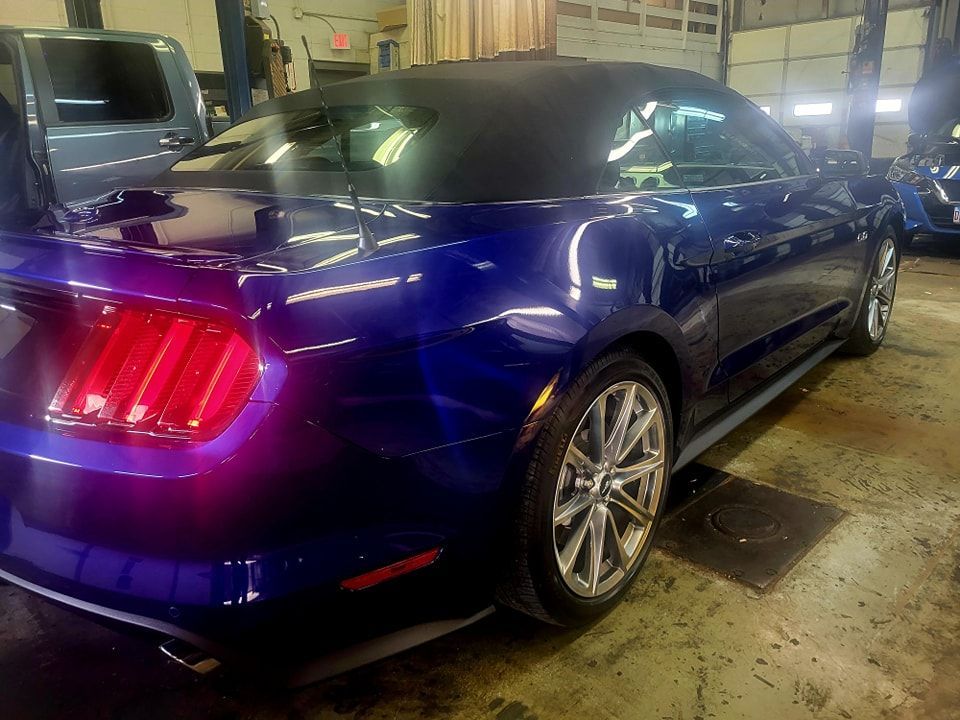 A blue mustang convertible is parked in a garage.