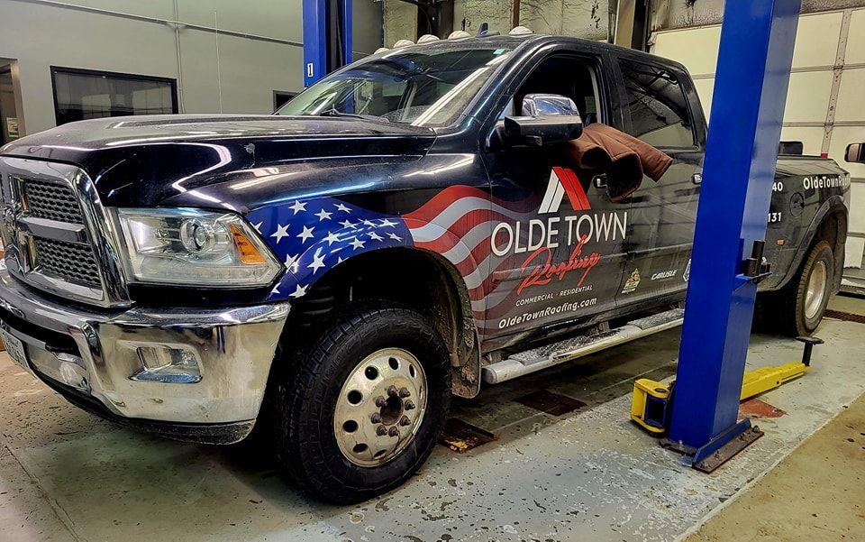 A black truck is parked on a lift in a garage.