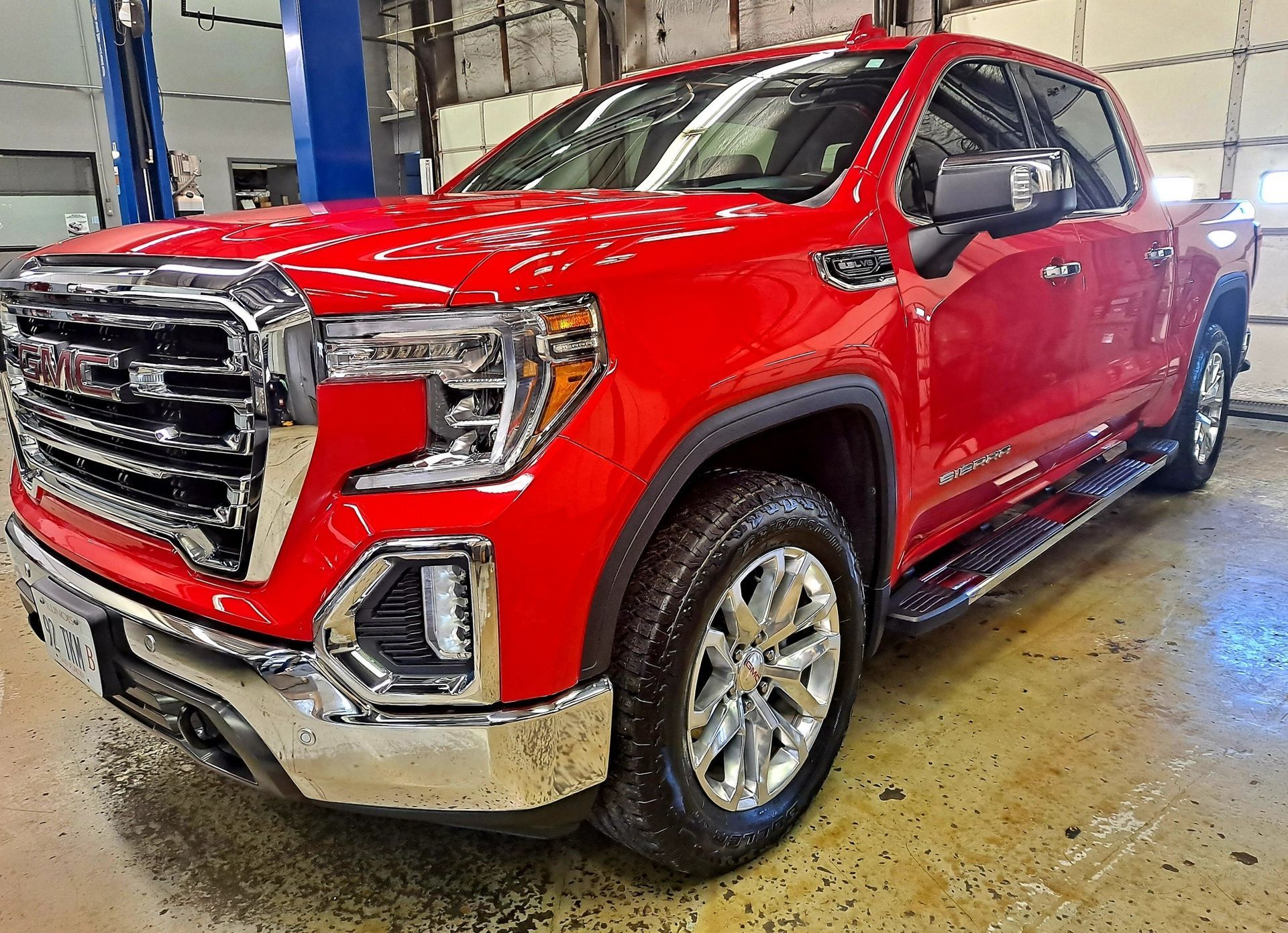 A red gmc sierra pickup truck is parked in a garage.