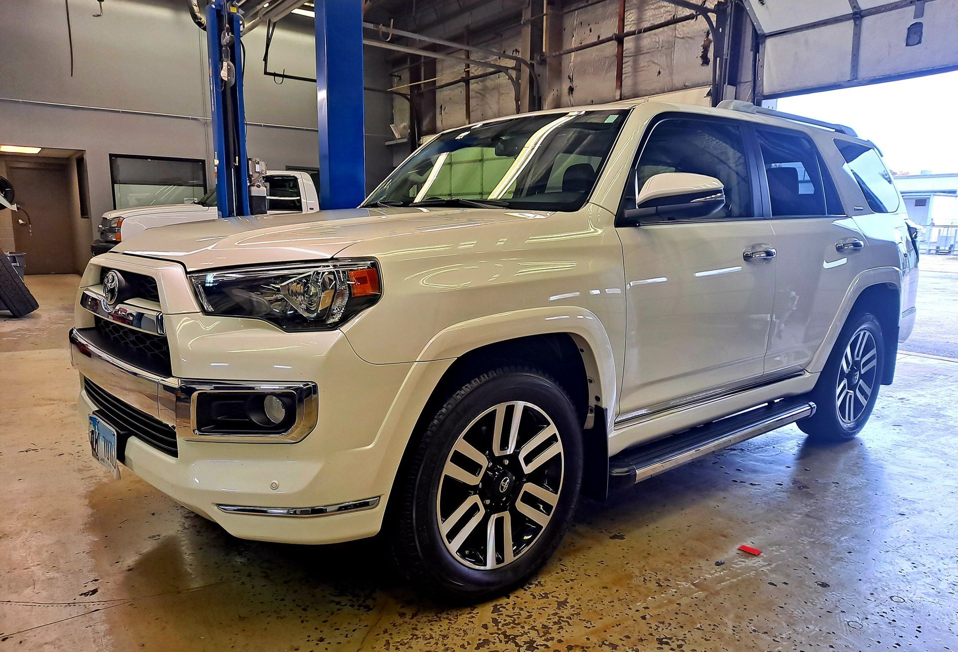 A white toyota 4runner is parked in a garage.