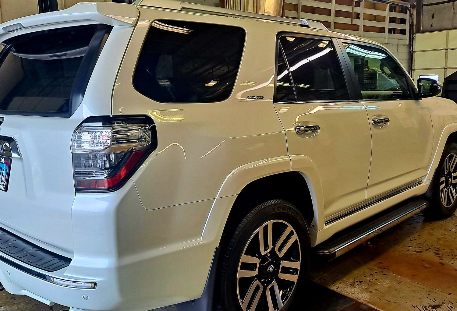 A white toyota 4runner is parked in a garage.
