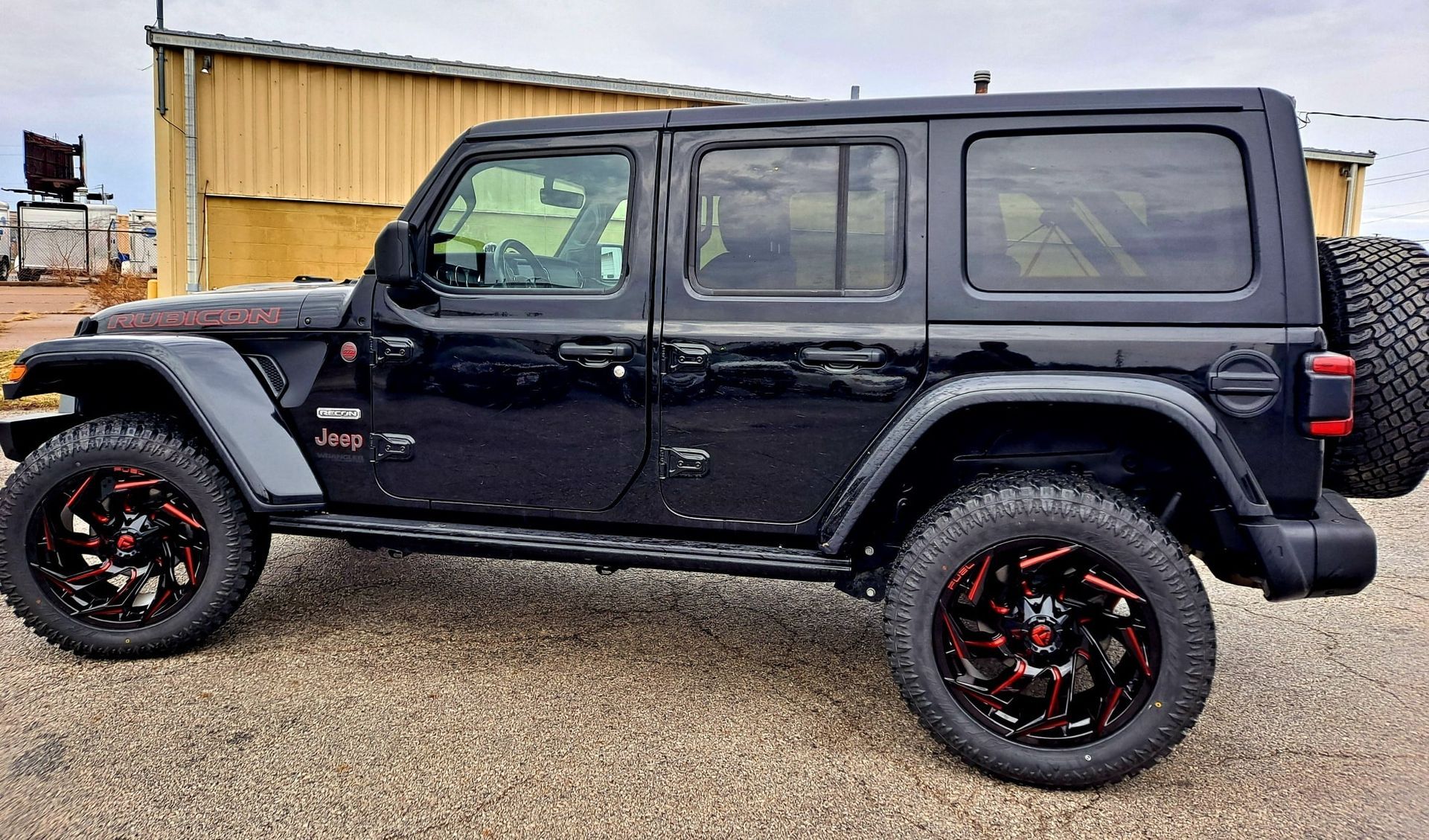 A black jeep wrangler is parked in front of a building.