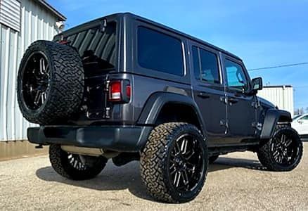 A black jeep wrangler is parked in front of a building.