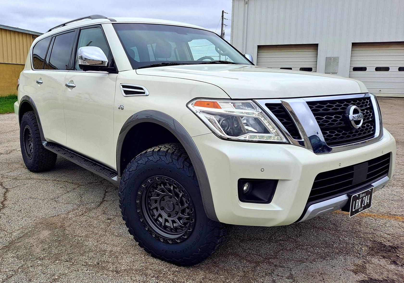 A white nissan patrol is parked in front of a garage.
