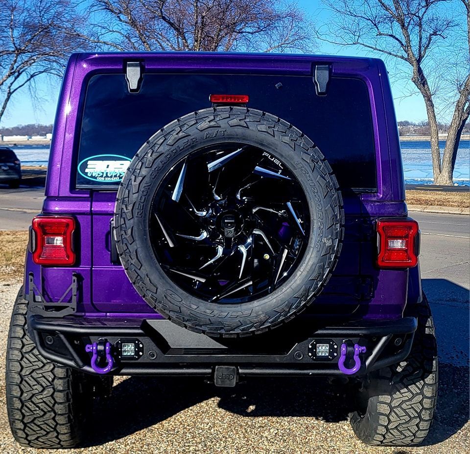 The back of a purple jeep with a spare tire