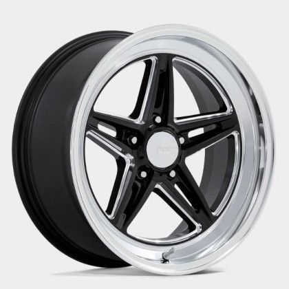 A close up of a black and chrome wheel on a white background.