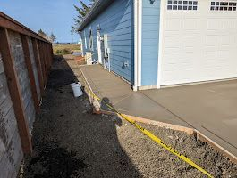 A concrete walkway is being built in front of a blue house.