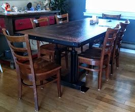 A dining room table and chairs are sitting on a wooden floor.