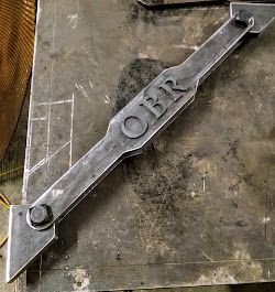 A piece of metal with the word ober written on it is sitting on a table.