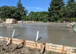 A concrete floor is being poured on a construction site.