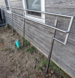 A stainless steel railing is installed on the side of a house.