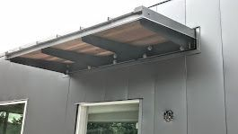 A canopy is attached to the side of a building next to a window.