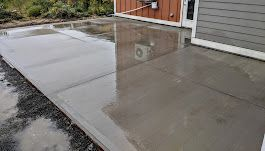 A concrete patio is being built in front of a house.