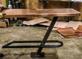 A copper table with a metal frame is sitting on the floor in a garage.
