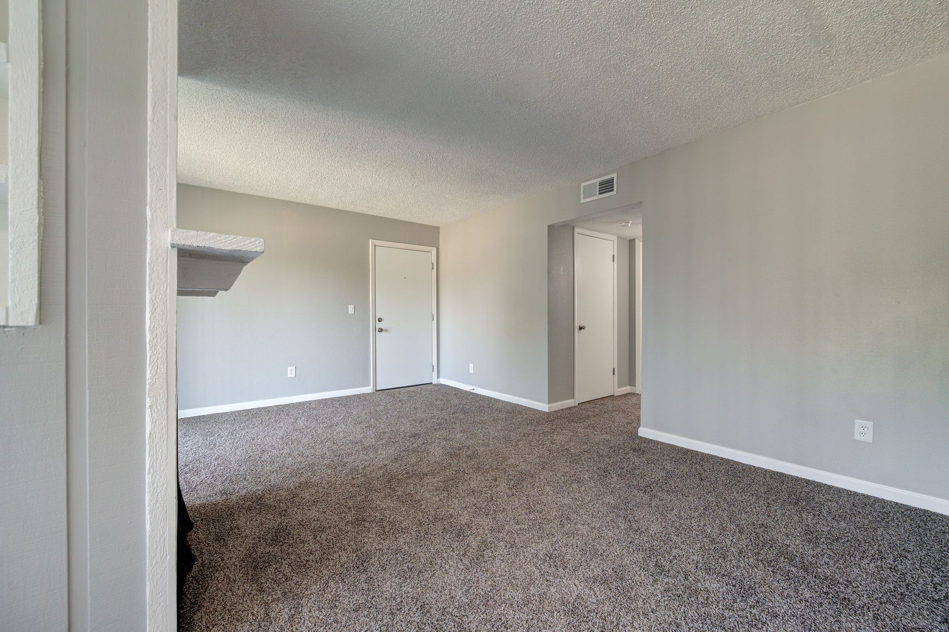 Empty room with gray walls and carpet, white doors, and a textured ceiling.