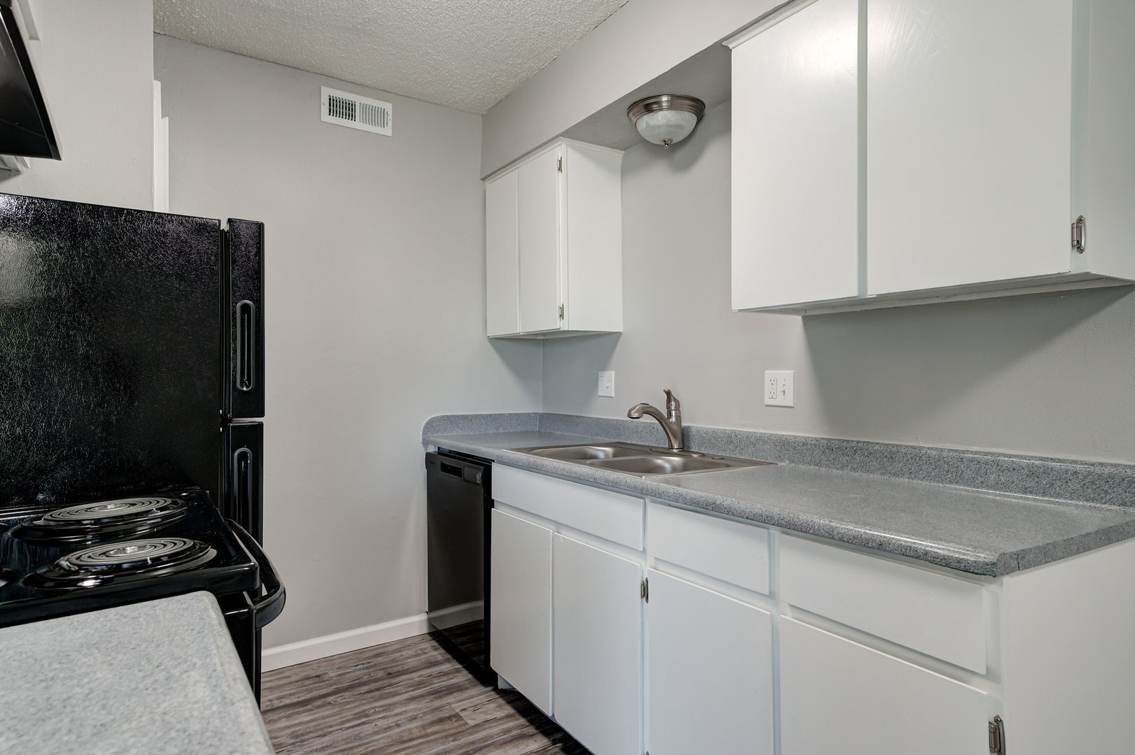 Kitchen with black appliances, white cabinets, and gray countertops and walls.