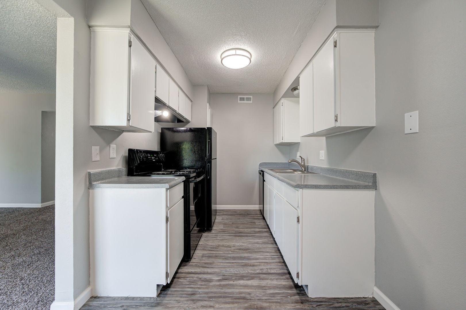 Kitchen with white cabinets, black appliances, and gray countertop.
